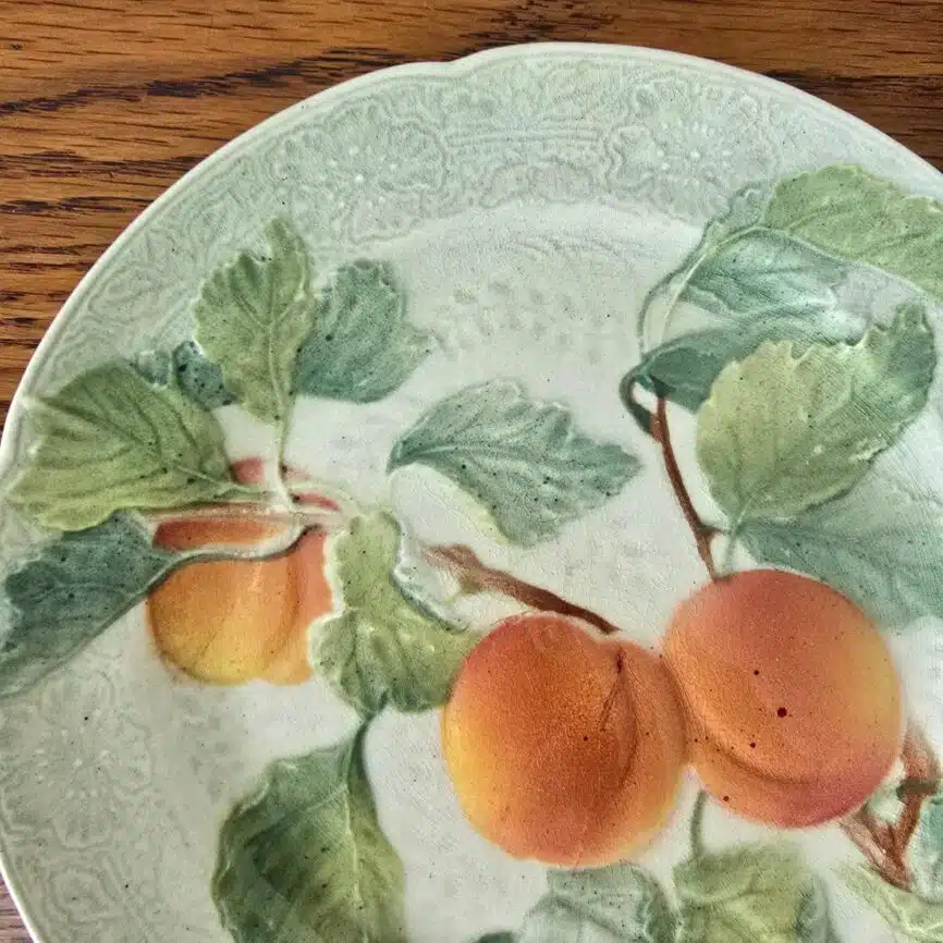 Assiette ancienne en barbotine St Clément, décor abricots en relief peint à la main – vue rapprochée