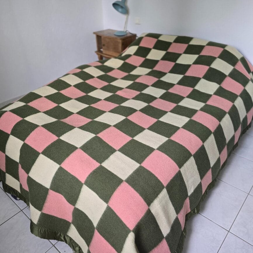 Vue d’ensemble du plaid vintage La Pyrénéenne déplié sur un lit, damier coloré.