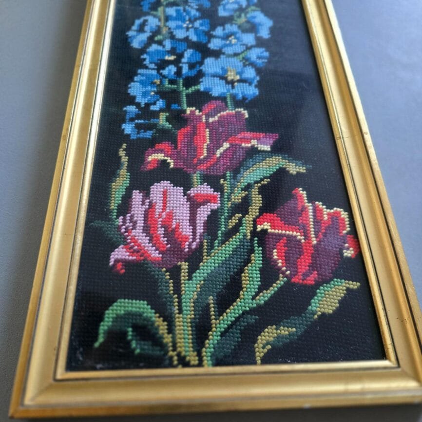 Vue en plongée du canevas floral, tulipes rouges et fleurs bleues en broderie sur fond noir
