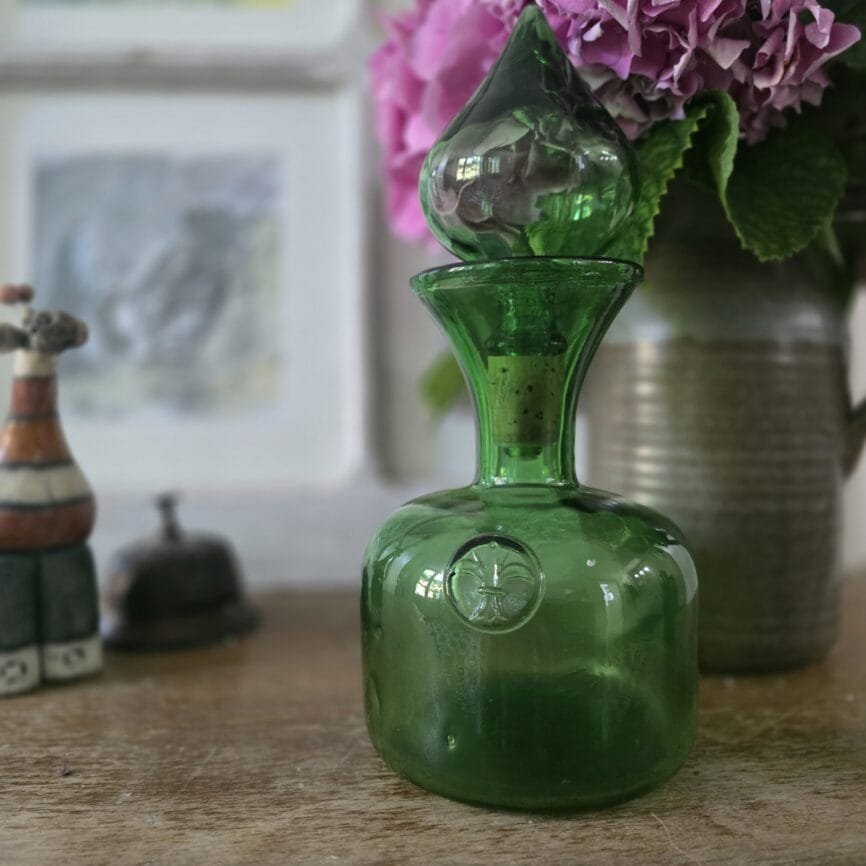 Gros plan sur la carafe debout, bouchon visible, lumière douce.