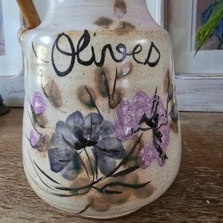 Vue rapprochée du pot à olives avec son couvercle, soulignant le décor floral violet, bleu et vert.
