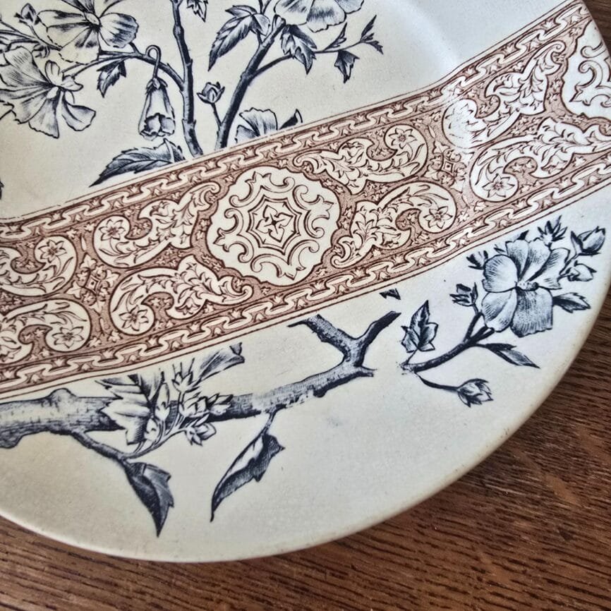 Détail décor assiette Longchamp ancienne fleurs bleues et frise brune.