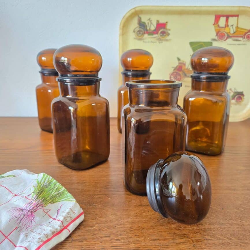Ensemble de pots en verre ambré Jacques Vabre posés sur table bois, couvercle sur le côté