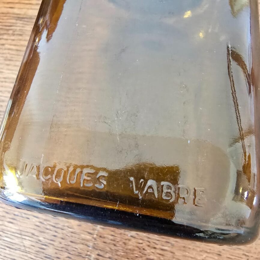 Détail de l’estampille « Jacques Vabre » en relief sur pot en verre, mise en avant du relief