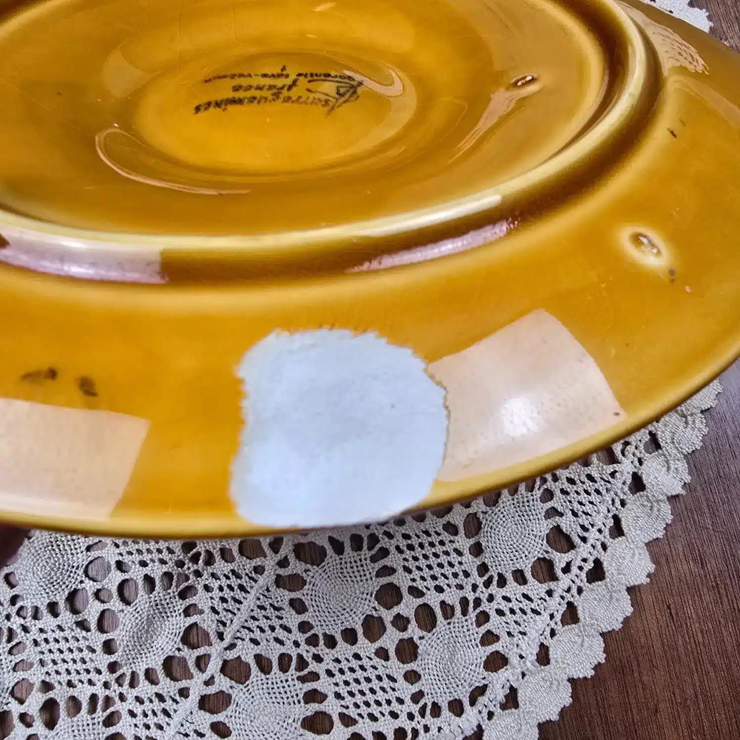 Dessous d’une assiette à huîtres Sarreguemines avec zones ébréchées visibles vue de 3/4