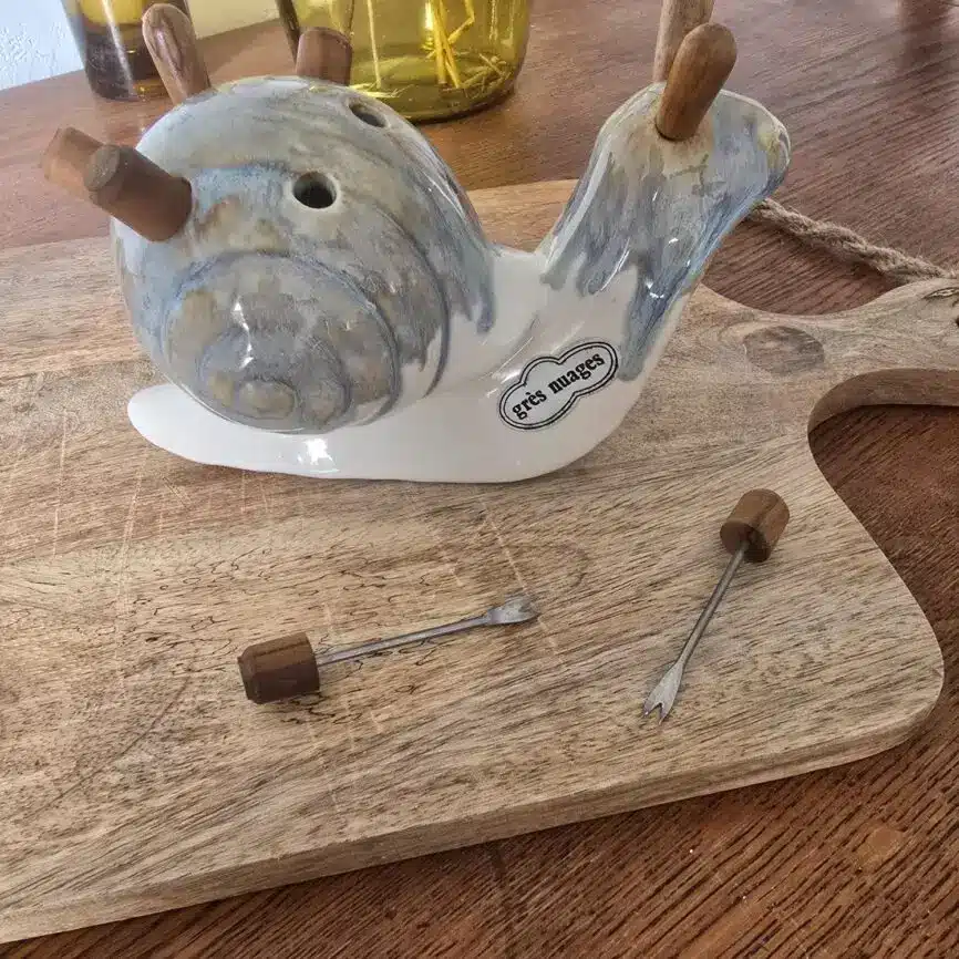 Escargot en grès vu de profil avec piques apéritifs.