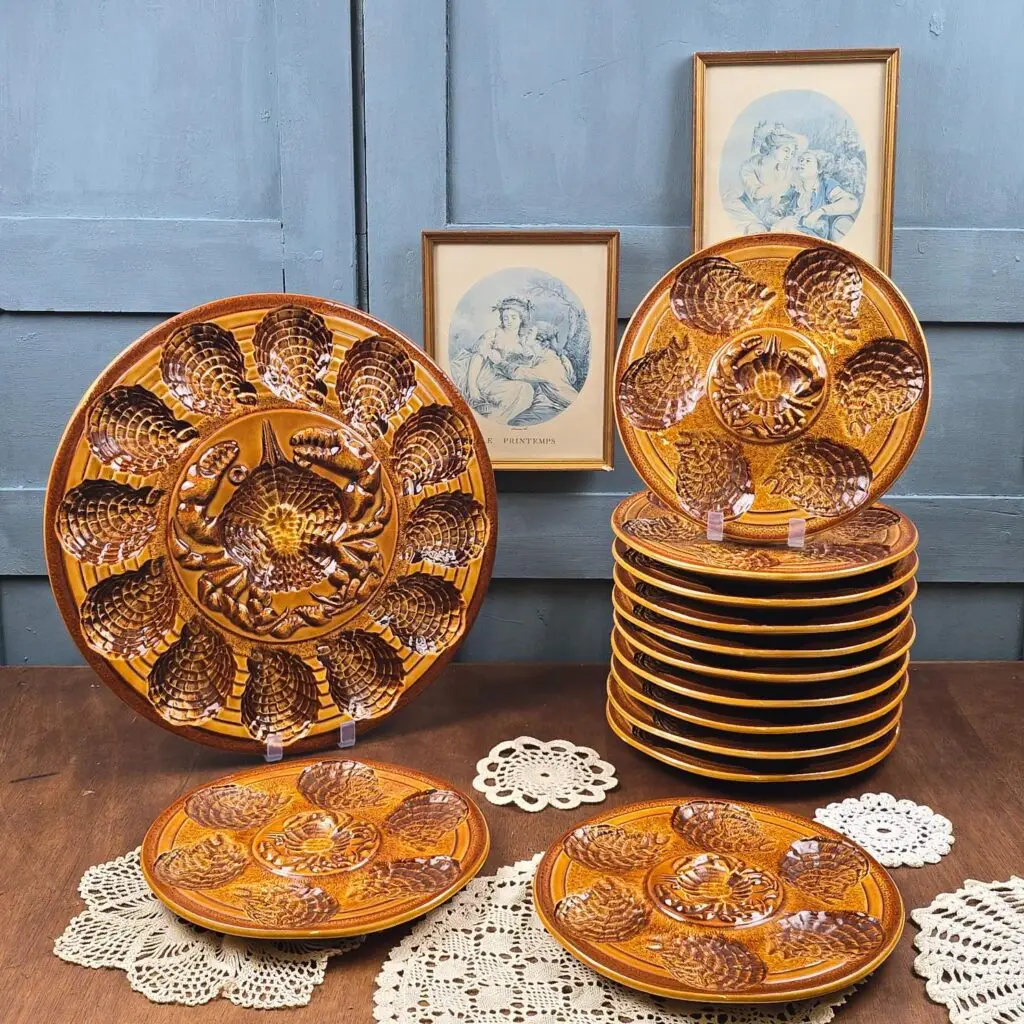 Service à huîtres Atelier du Revernay France, 12 assiettes et un grand plat de service en faïence barbotine marron.