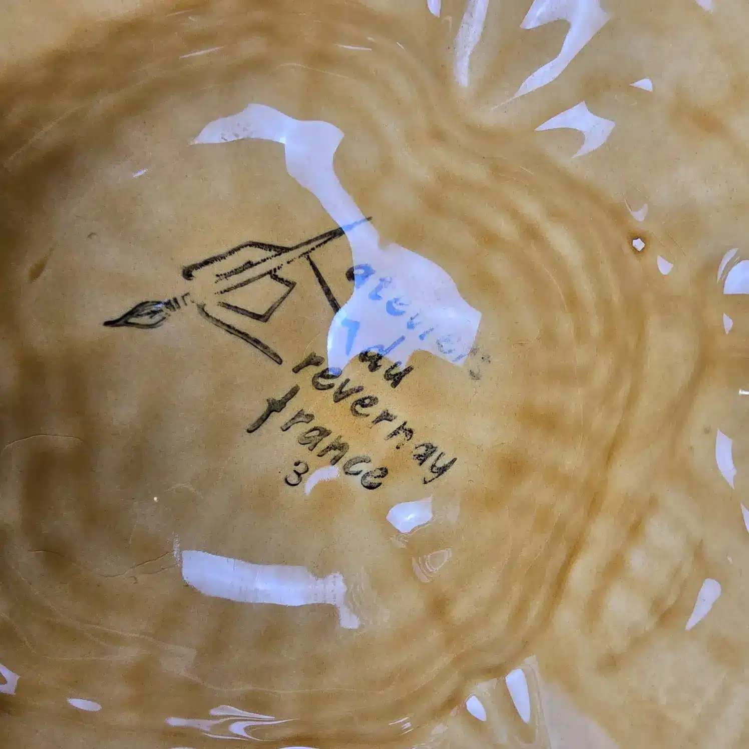 Zoom de l'estampille Atelier du Revernay France visible sous une assiette.