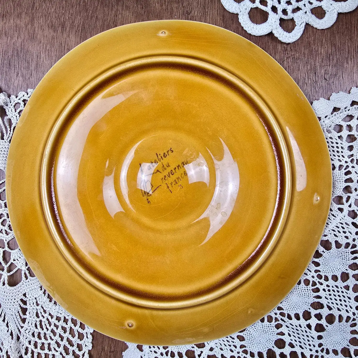 Dessous d’une assiette à huîtres Atelier du Revernay France en barbotine marron.