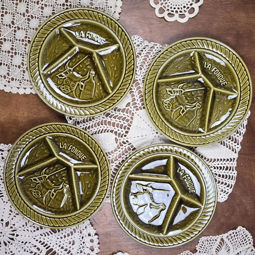 Lot de quatre assiettes à fondue vintage Sarreguemines en faïence vernissée verte, décor relief vache et bouteille de vin.
