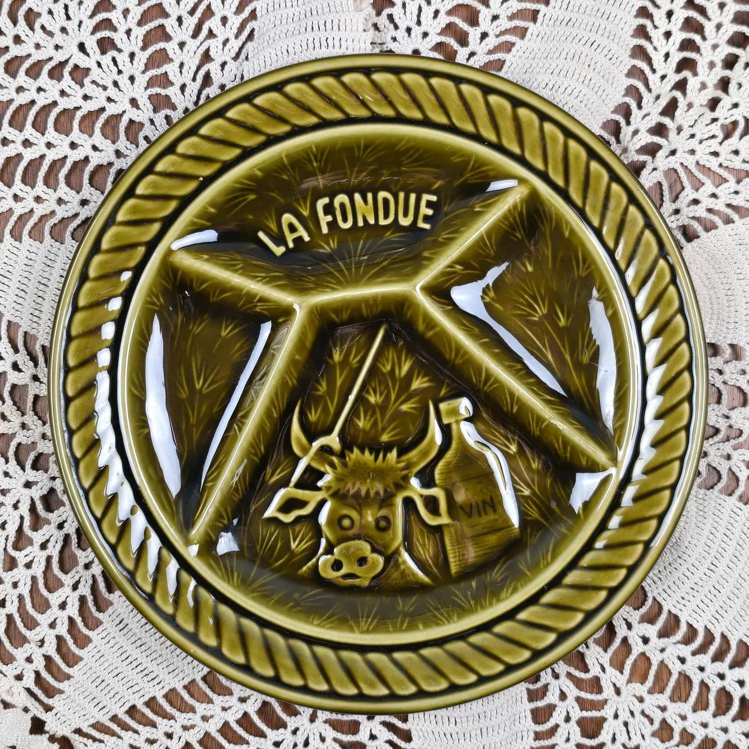 Assiette à fondue Sarreguemines vintage en faïence émaillée verte, vue de dessus avec décor en relief La Fondue.