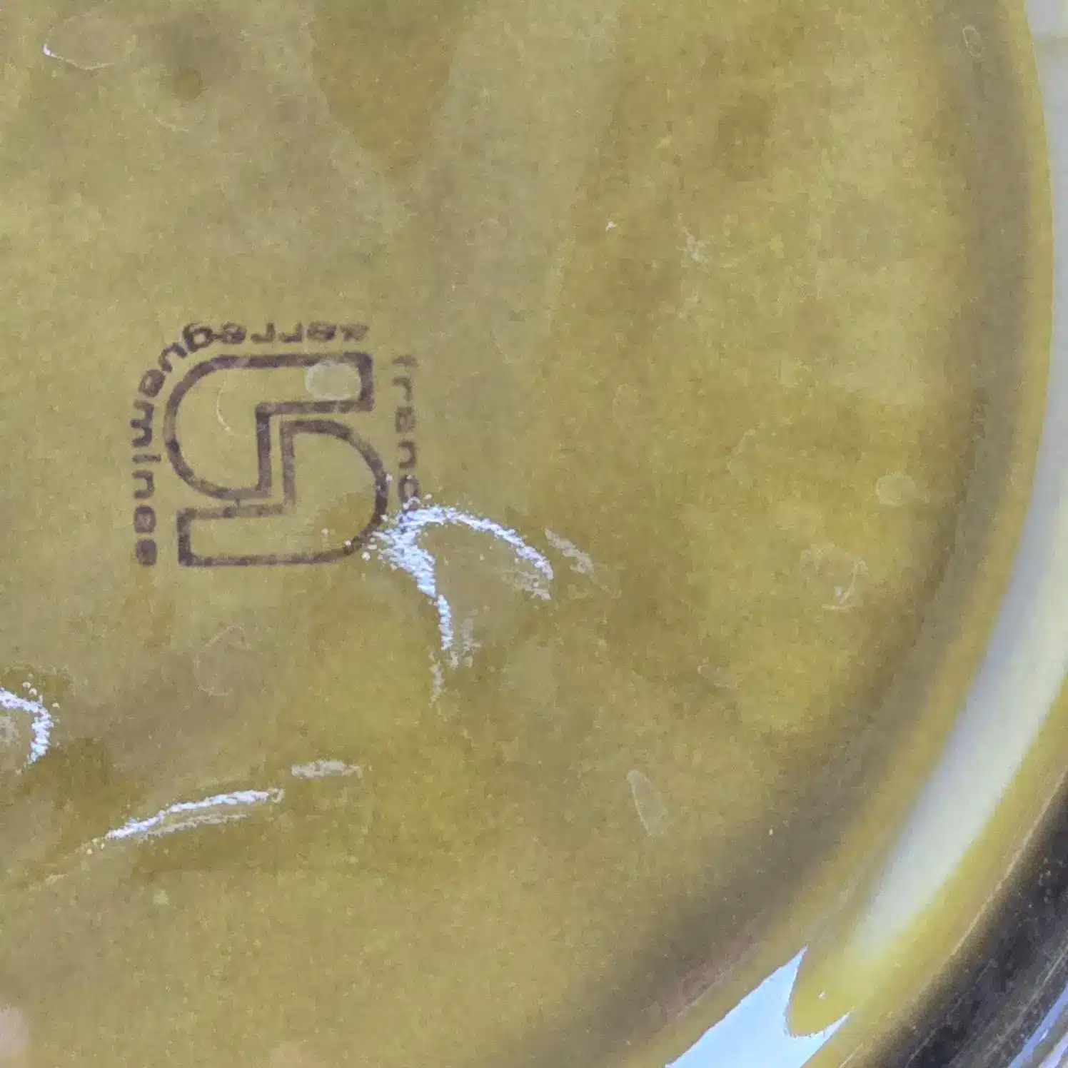 Estampille Sarreguemines France visible sous une assiette à fondue vintage en faïence vernissée.
