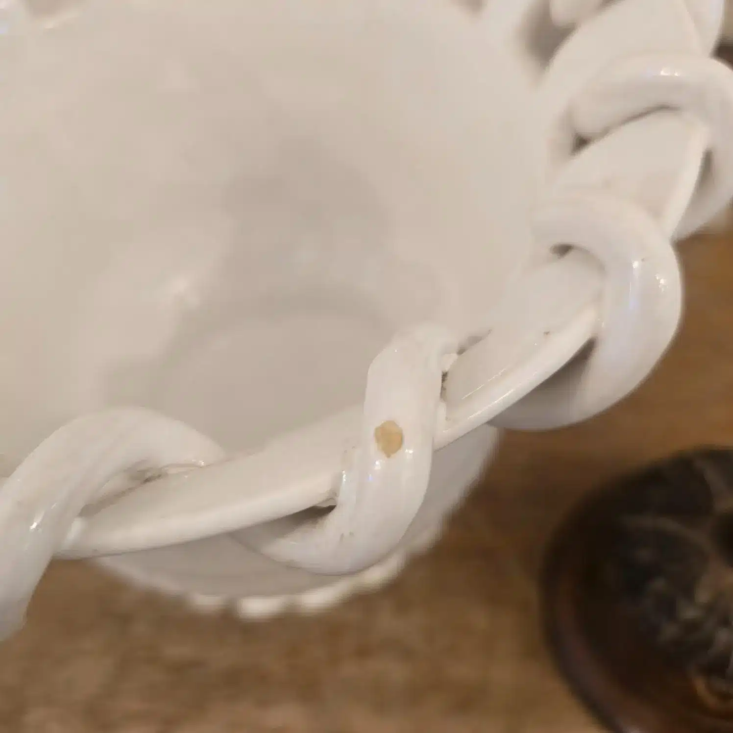 Détail du bord torsadé du cache-pot en faïence Malicorne Émile Teissier, petite ébréchure visible sur le bord