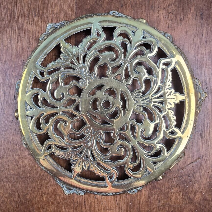 Vue complète du dessous de plat, illustrant le motif floral symétrique et le relief du métal.