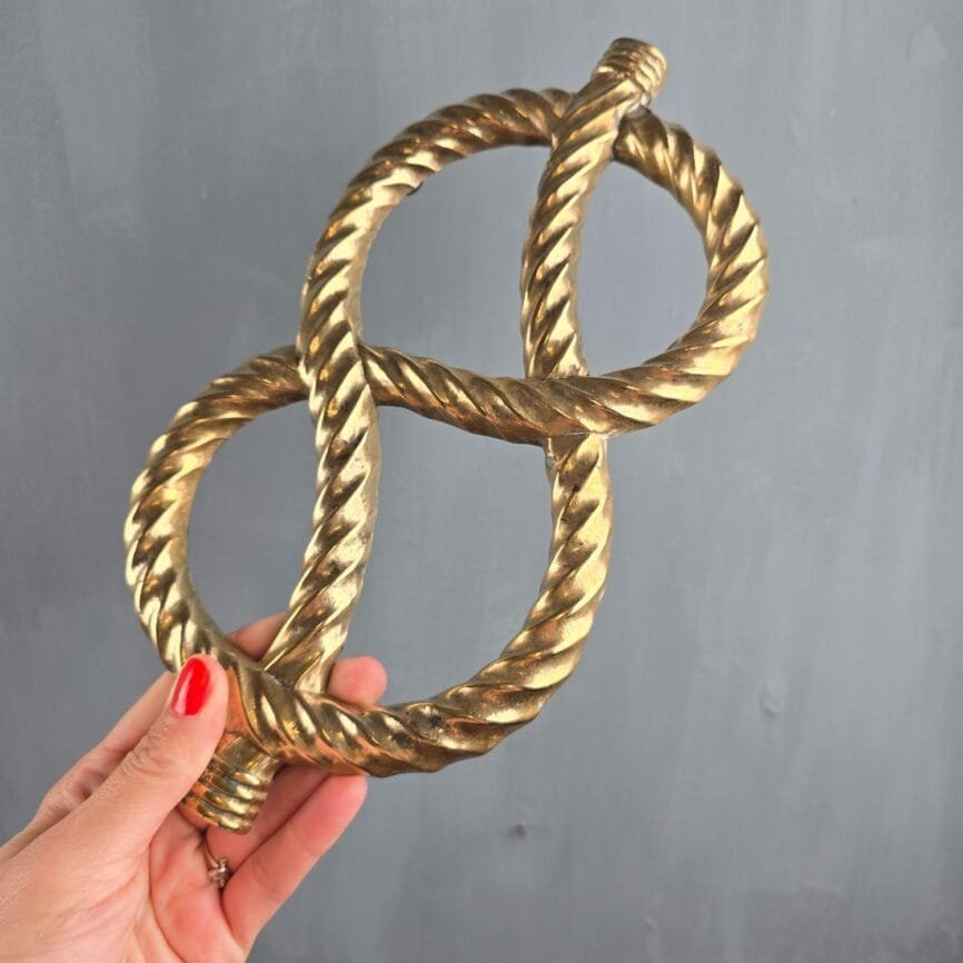 Dessous de plat vintage en laiton en forme de nœud de corde tenu en main