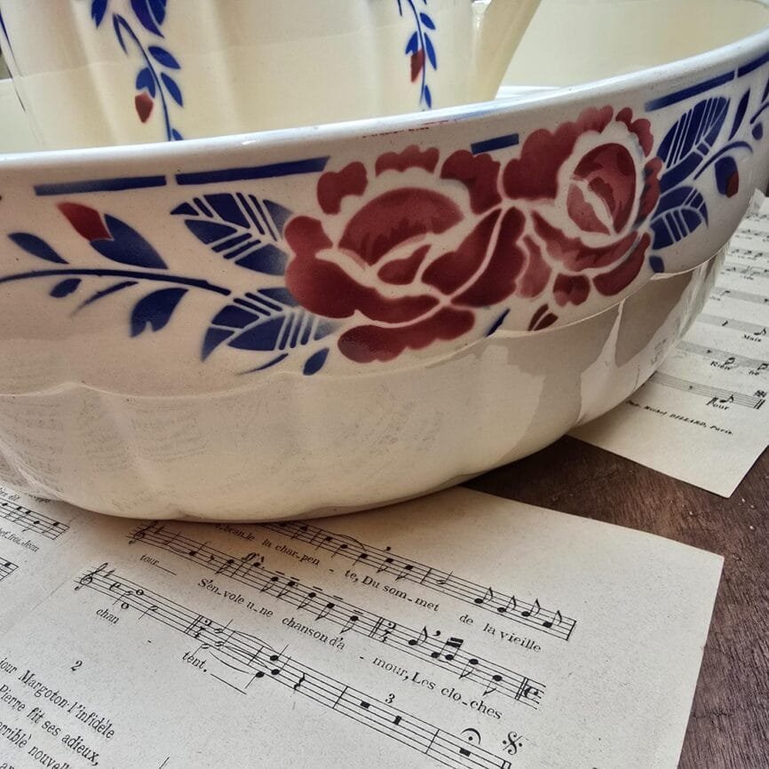 Détail du décor peint au pochoir rouge et bleu sur le bord de la bassine Luneville Les Roses.