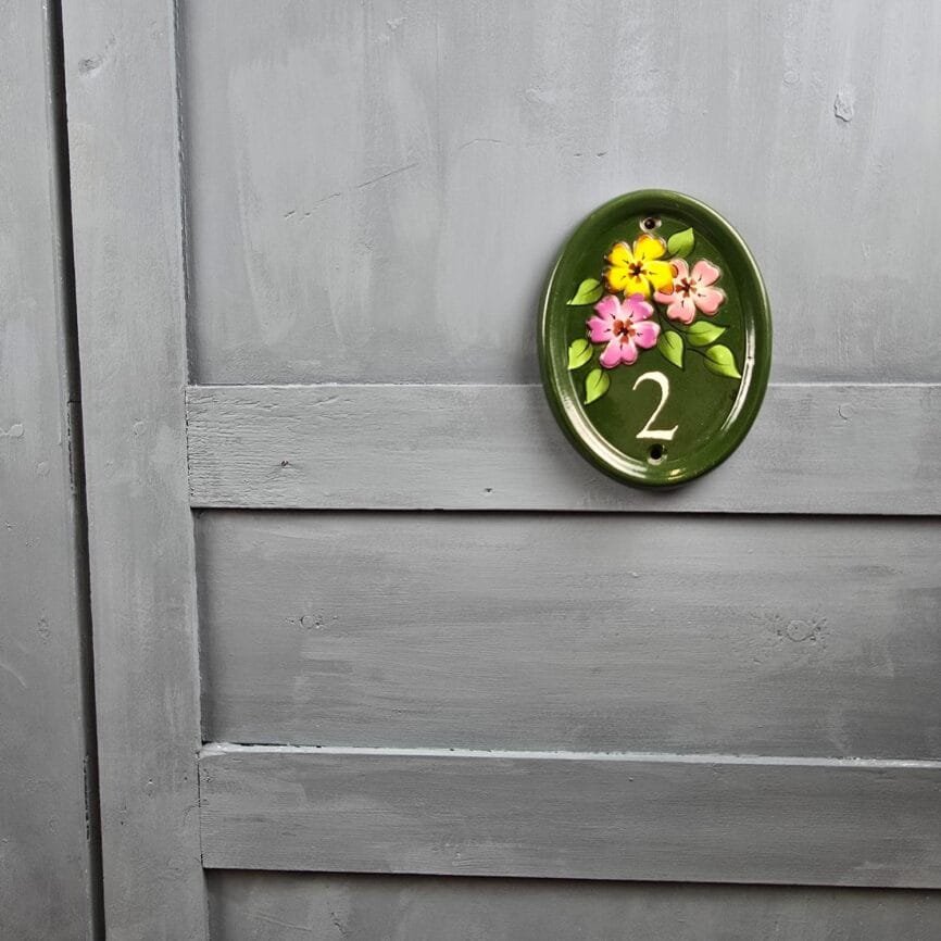 Vue de face de la plaque de porte N°2 signée Mike sur fond gris.