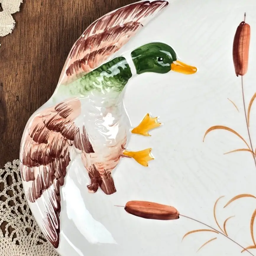 Gros plan sur le canard en relief peint à la main, aux teintes vert, brun et jaune.