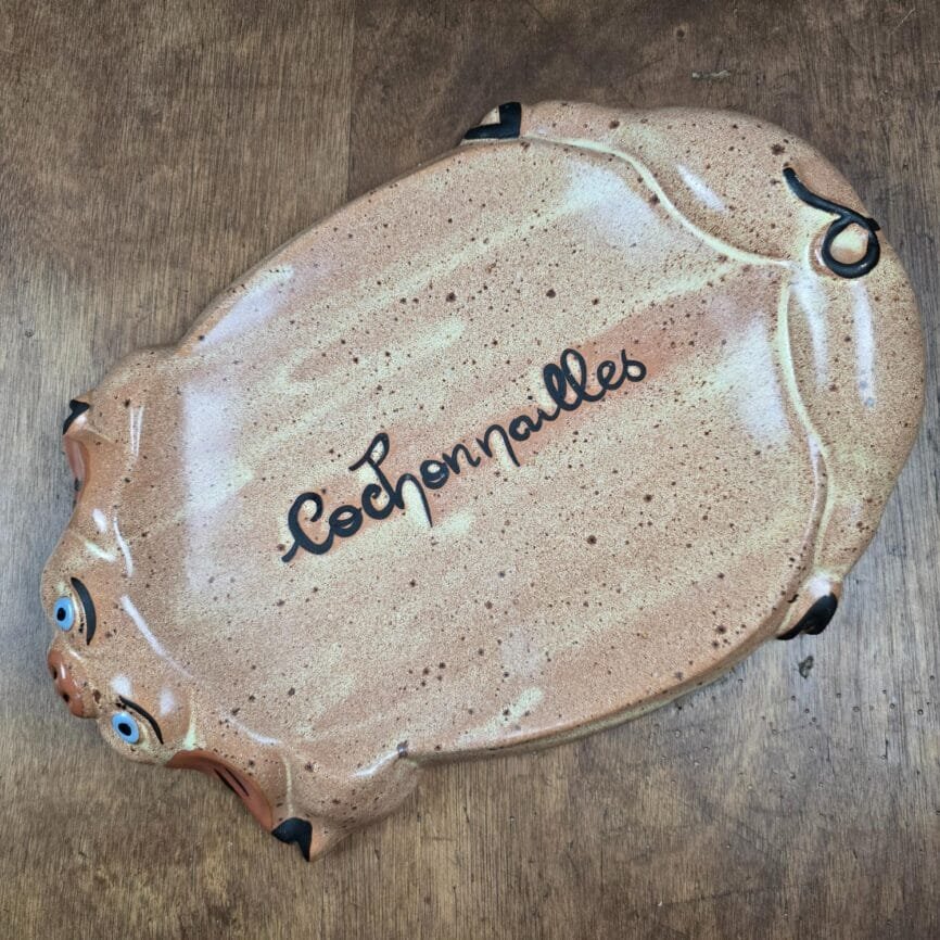Vue complète du plat “Cochonailles” avec décor beige moucheté et expression faciale peinte à la main.