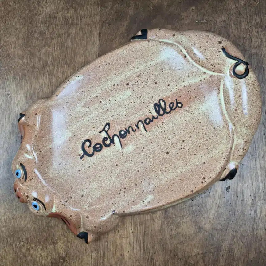Vue complète du plat “Cochonailles” avec décor beige moucheté et expression faciale peinte à la main.