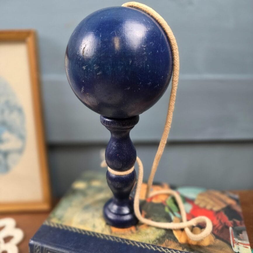 Bilboquet bleu marine présenté sur des livres, vue rapprochée.