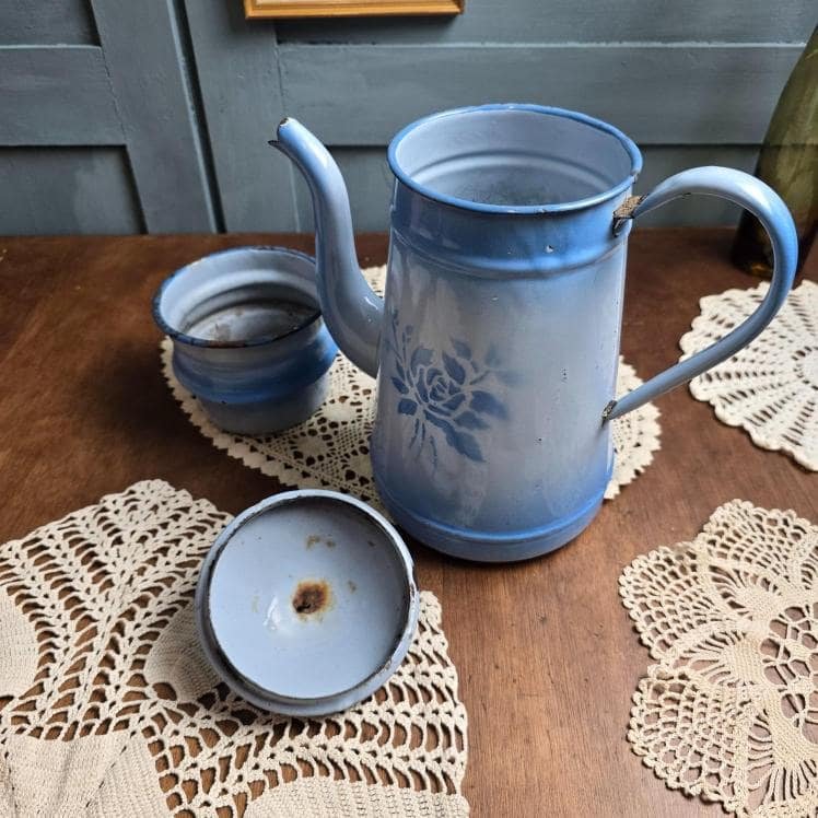 Ensemble complet de la cafetière bleue émaillée ouverte, couvercle et filtre visibles sur un napperon ancien.