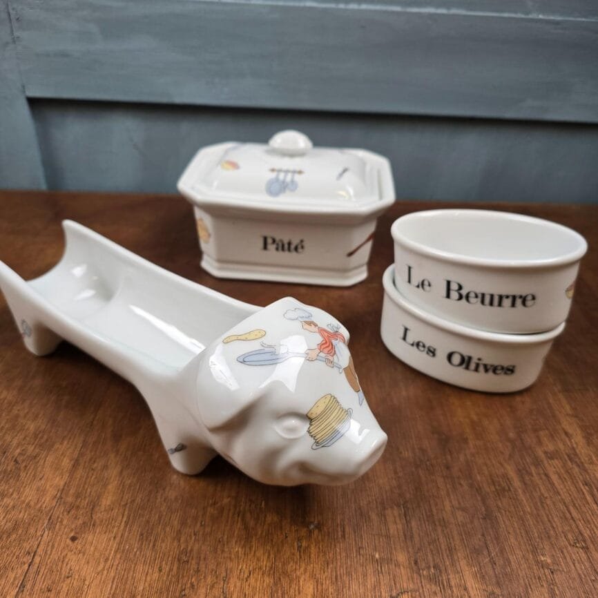 Ensemble des pièces disposées hors de l’écrin sur fond bois, cochon en avant vue de profil.