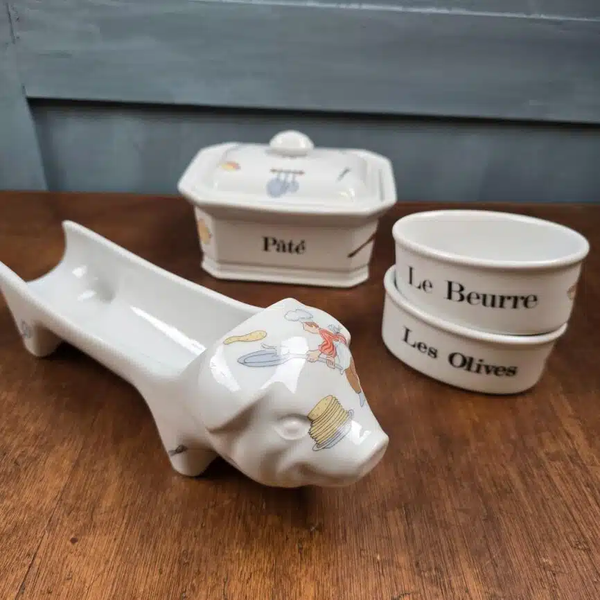 Ensemble des pièces disposées hors de l’écrin sur fond bois, cochon en avant vue de profil.