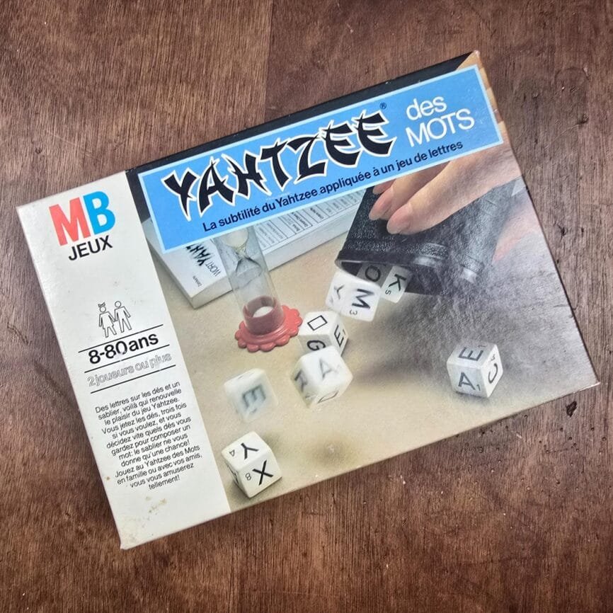 Jeu vintage Yahtzee des Mots MB, boîte illustrée années 80 posée sur table en bois.