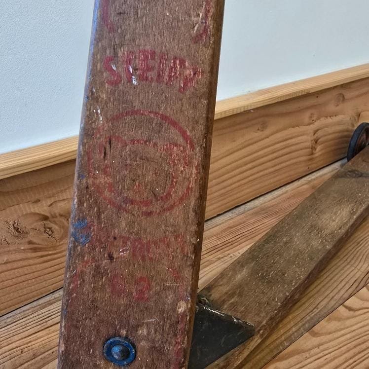 Détail du logo Steiff rouge sur le bois de la trottinette ancienne, estampille visible avec tête d’ours.