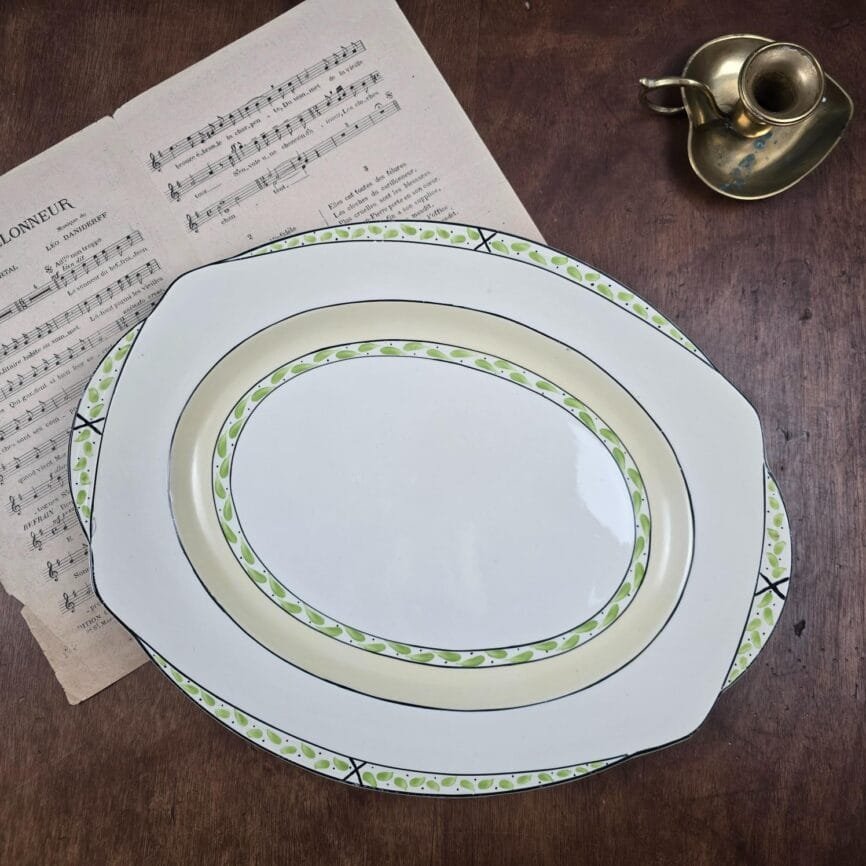 Plat anglais ovale Burleigh Ware présenté sur une table avec partition ancienne.