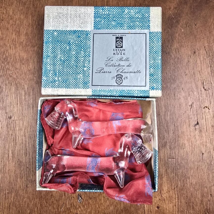 Vue d’ensemble du duo de repose-couteaux présentés sur leur tissu rouge d’origine.