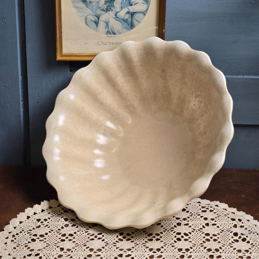 Grand saladier ancien Jules Vieillard & Cie Bordeaux en porcelaine opaque, forme coquillage, à la patine crème nuancée, posé sur une table en bois clair.