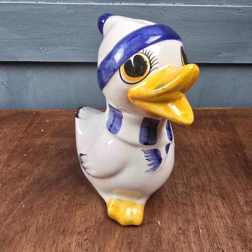 Vue de trois quart de la tirelire vintage en forme de canard montrant son grand sourire.