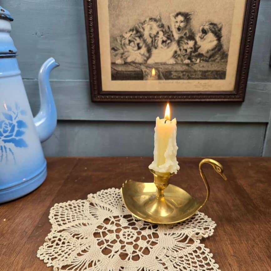 Bougeoir ancien en laiton en forme de cygne, avec bougie allumée, ambiance vintage et poétique.