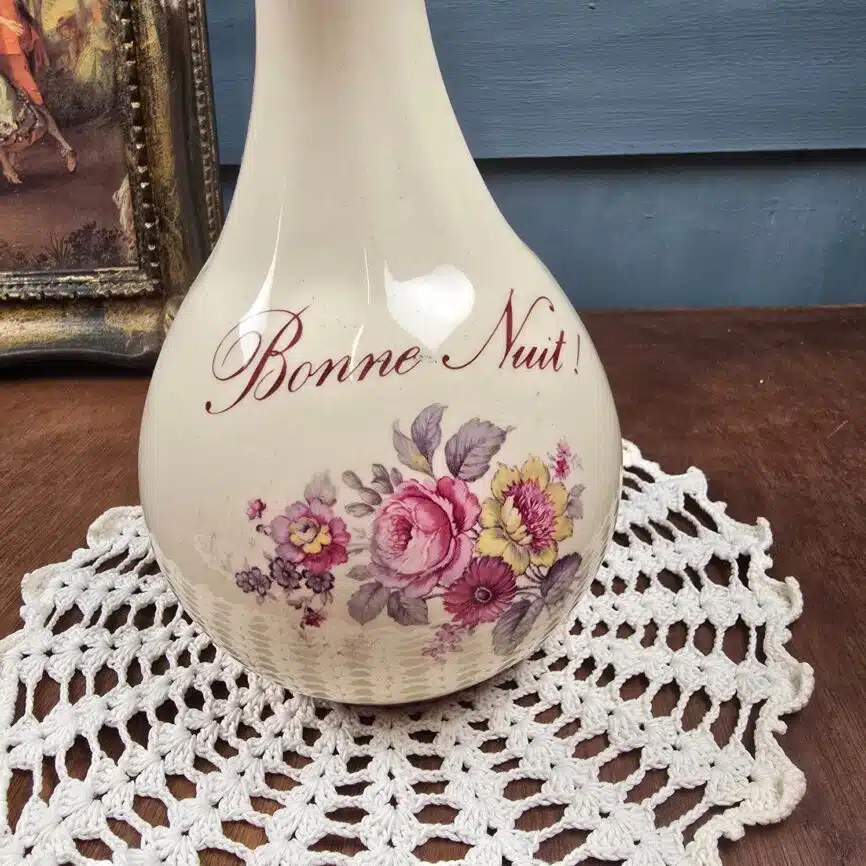 Gros plan sur le décor fleuri et l’inscription « Bonne Nuit ! » de la carafe de nuit ancienne.