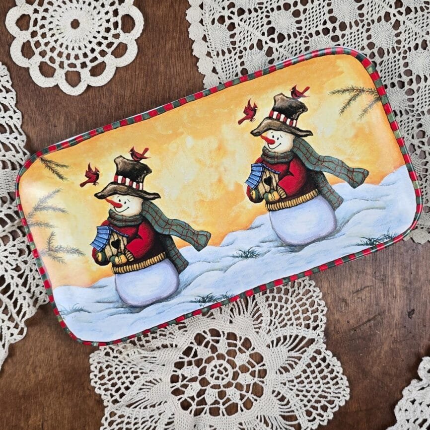 Plat rectangulaire décoratif d’hiver avec bonhommes de neige, vue du dessus sur fond bois et napperon ancien