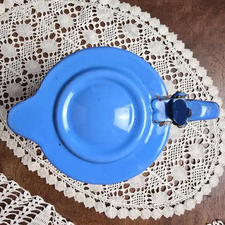Vue de dessus de la verseuse émaillée bleue, couvercle articulé en métal et anse arrondie, émail brillant d’origine.