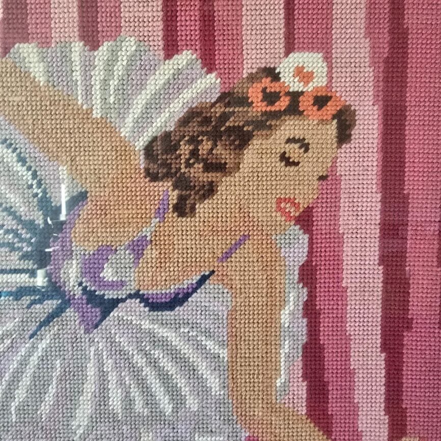 Point de croix ancien montrant une danseuse en plein mouvement devant un fond évoquant un rideau