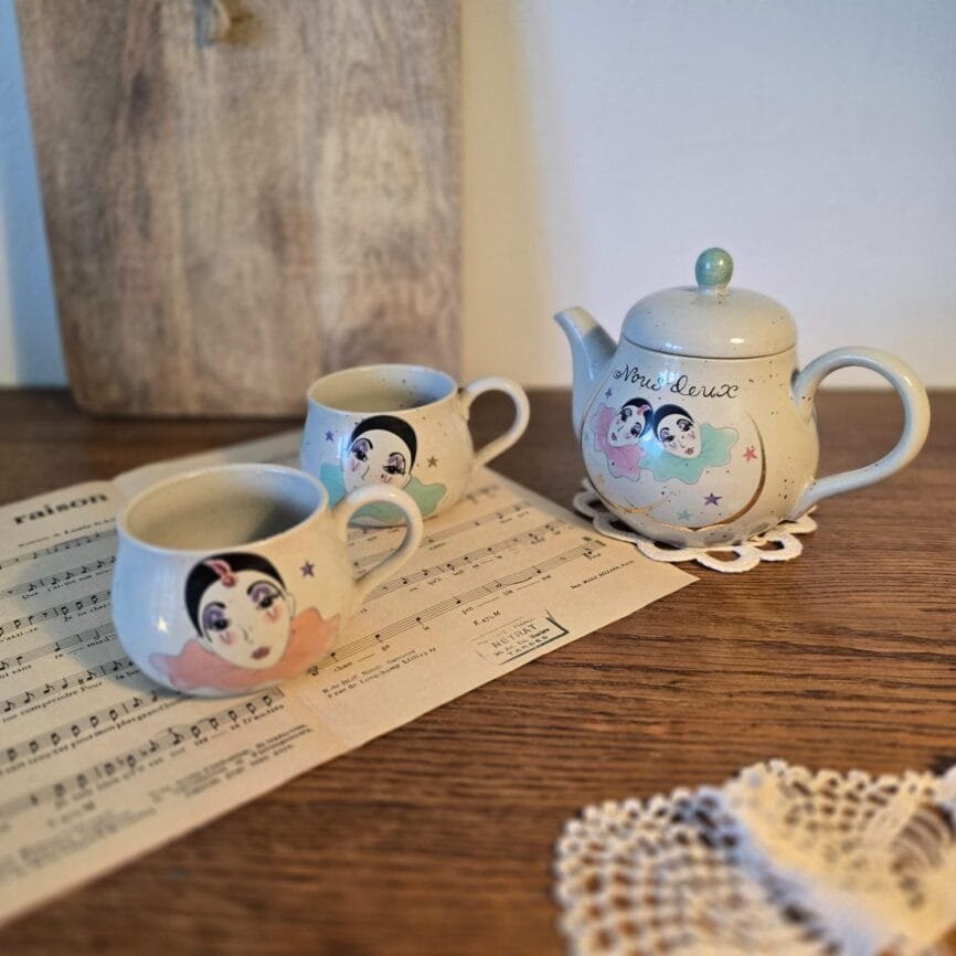 Tasse vintage Pierrot rose posée sur partition de musique, décor poétique