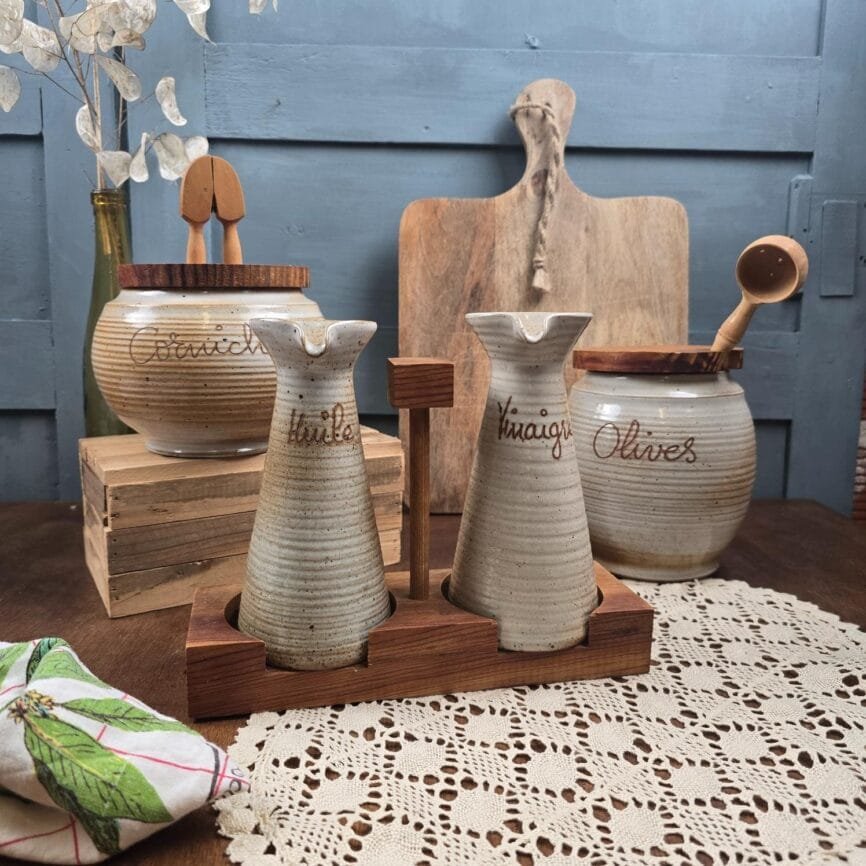 Huile, vinaigre, pot à cornichons et pot à olives sur table en bois Grès du Marais France brocante vintage.