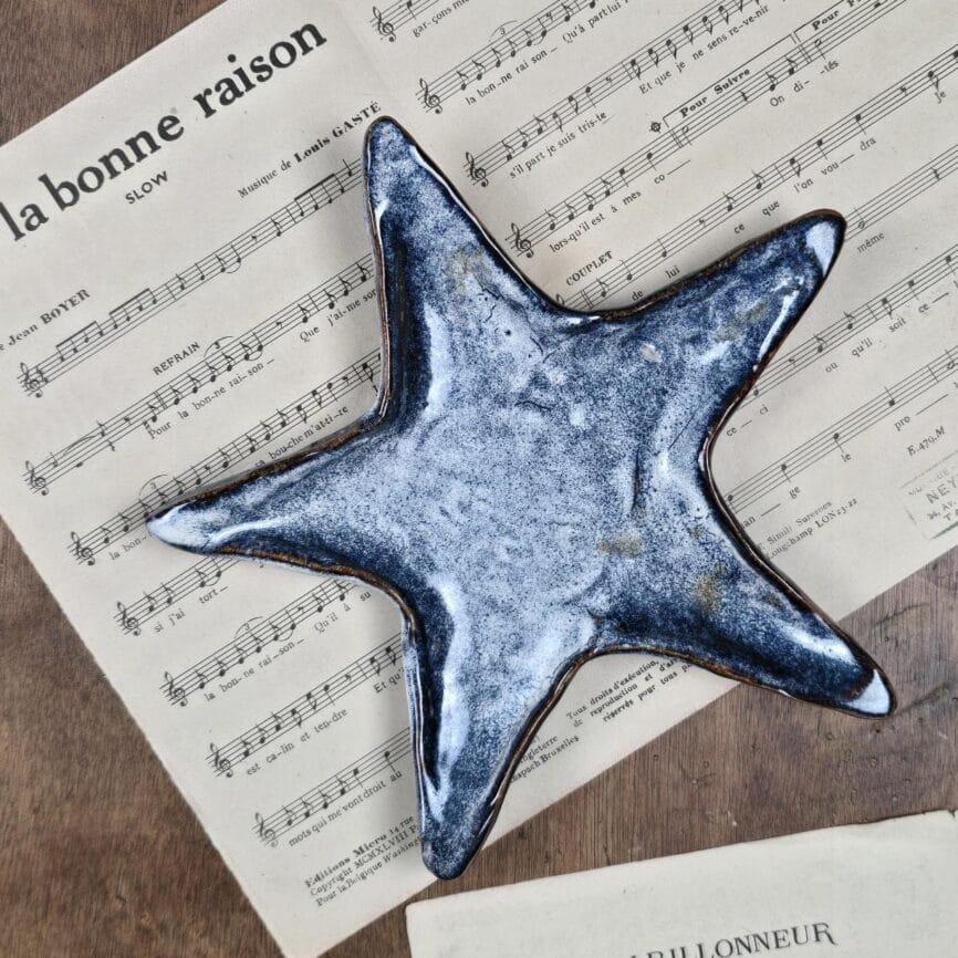 Étoile en céramique émaillée posée sur une partition ancienne, vue de dessus