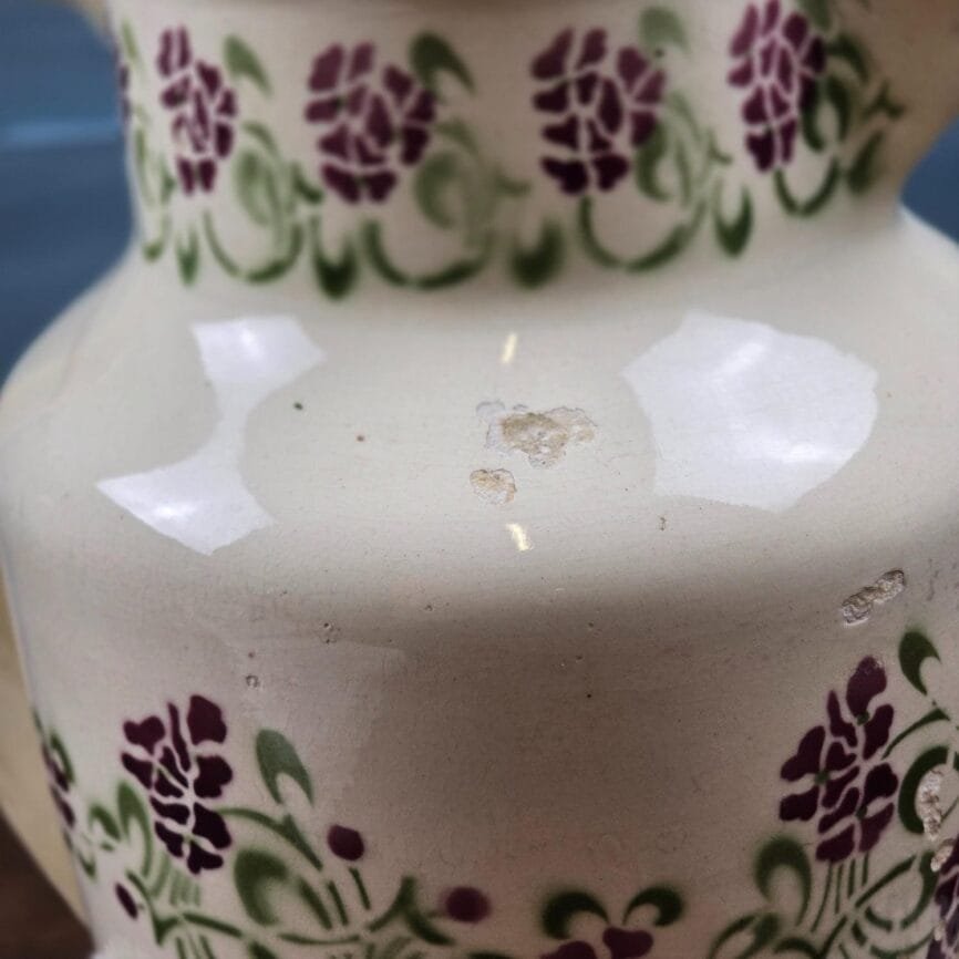 Détail du col du broc Choisy-le-Roi avec frise florale au pochoir violet et vert.