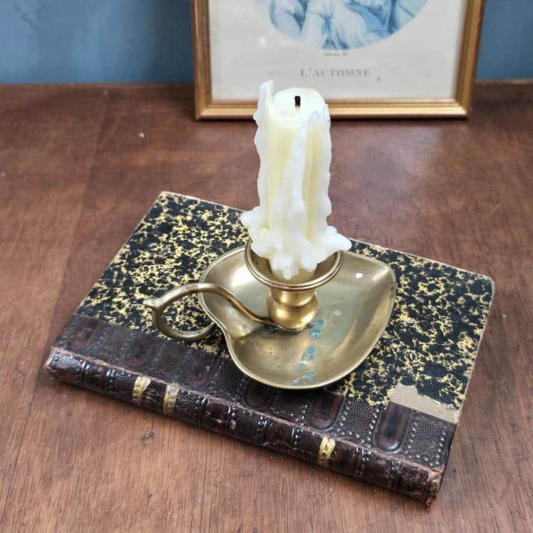 bougeoir laiton en forme de cœur vintage posé sur un livre ancien