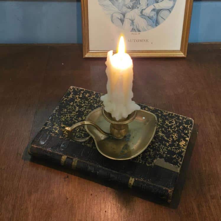bougeoir laiton en forme de cœur vintage posé sur un livre ancien, bougie allumée