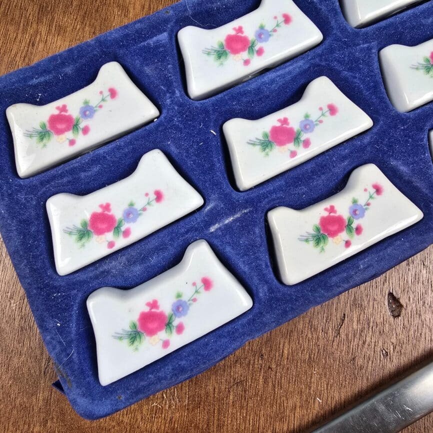 Vue rapprochée des reposes couteaux vintage en porcelaine blanche motif fleurs