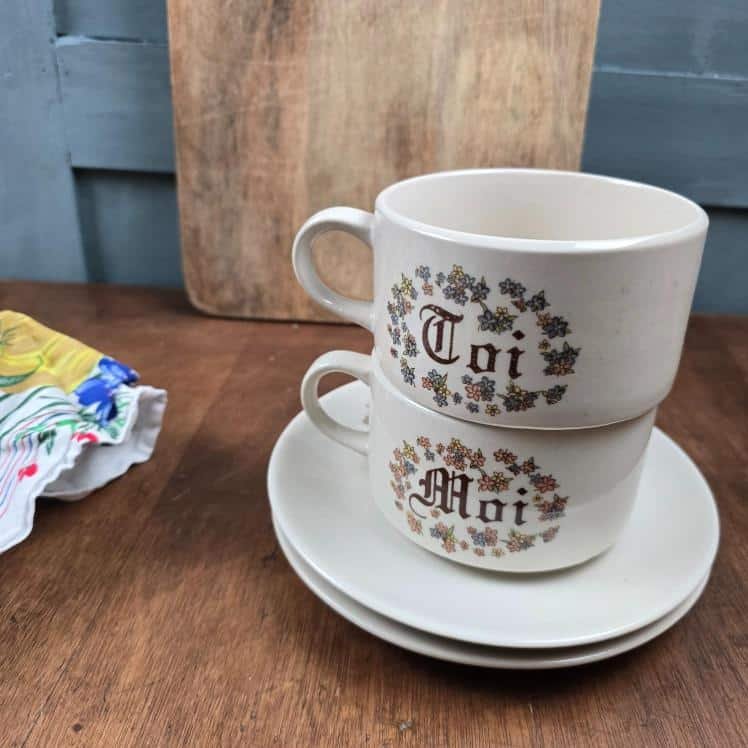 Tasses vintage Toi & Moi en grès superposées avec soucoupes sur table en bois