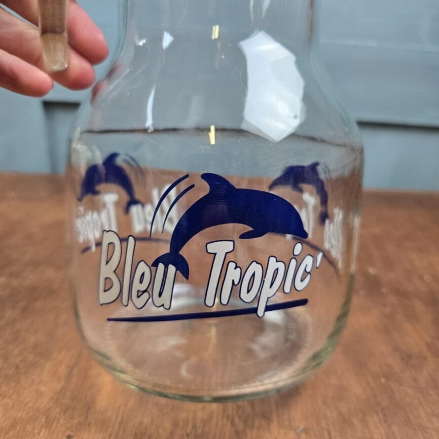 Grande carafe vintage Bleu Tropic, ambiance bar et bistro, zoom sur le décor dauphin et l'inscription "Bleu Tropic"