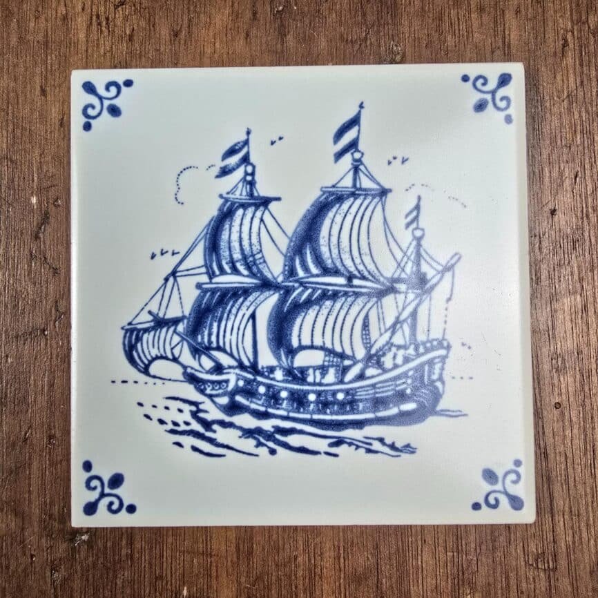 Carreau ancien Royal Mosa Holland – Voilier bleu Delft sur table en bois