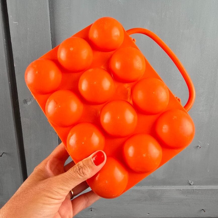 Boîte à œufs vintage plastique orange tenu en main